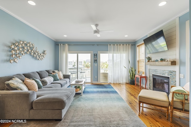 living room featuring hardwood / wood-style floors, crown molding, and a tile fireplace