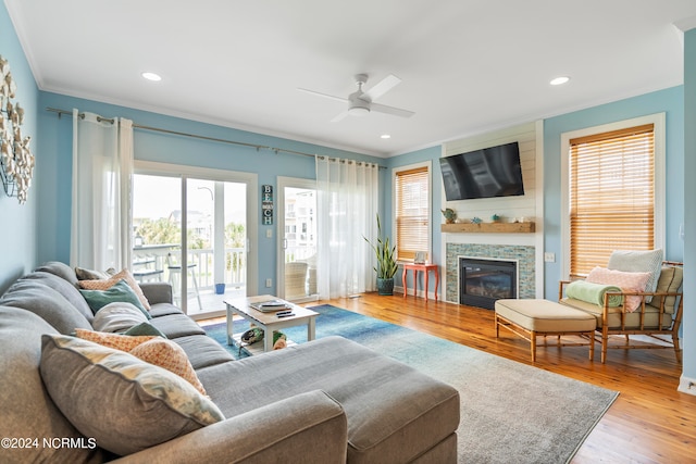 living room with ceiling fan, a fireplace, light hardwood / wood-style flooring, and a healthy amount of sunlight