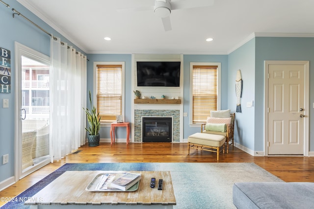 living room featuring light hardwood / wood-style flooring, a fireplace, ornamental molding, and ceiling fan