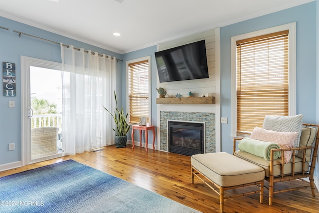 living area with a tiled fireplace, crown molding, hardwood / wood-style floors, and a wealth of natural light