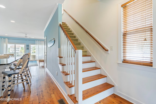 staircase featuring crown molding, light wood-type flooring, and ceiling fan