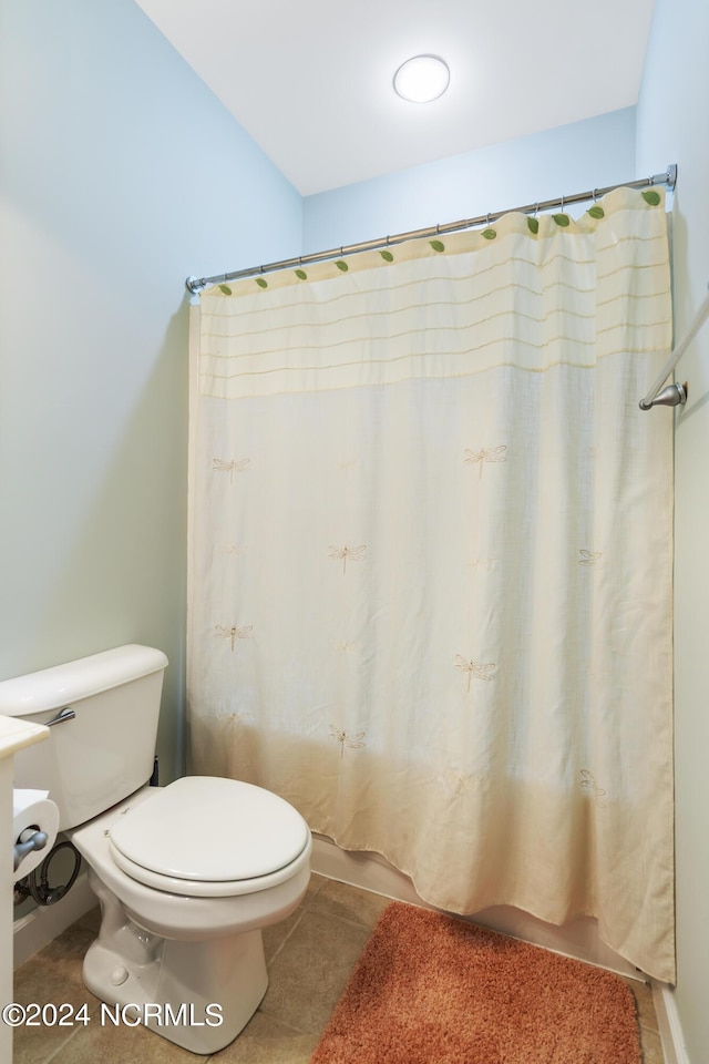 bathroom featuring a shower with curtain, toilet, and tile patterned flooring