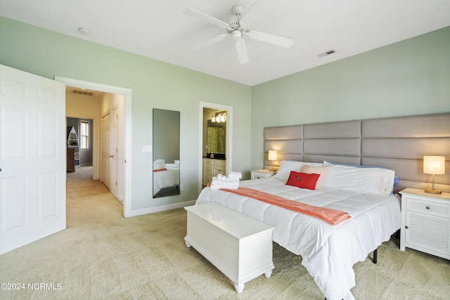 bedroom with ceiling fan, connected bathroom, and light carpet