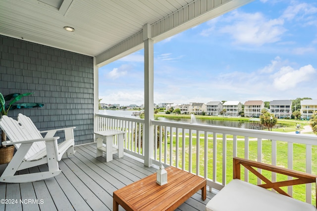 deck featuring a water view and a lawn