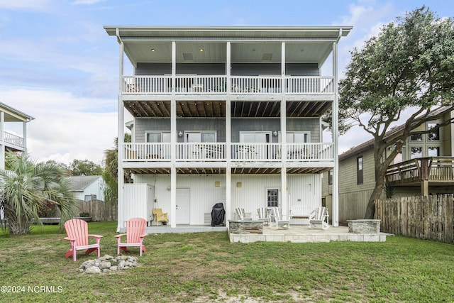 back of house featuring a yard, a patio area, a balcony, and an outdoor fire pit