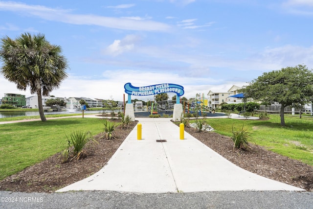 view of property's community featuring a water view, a playground, and a lawn