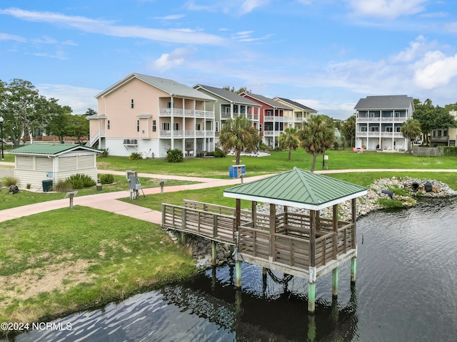 dock area featuring a balcony, a water view, a gazebo, and a lawn