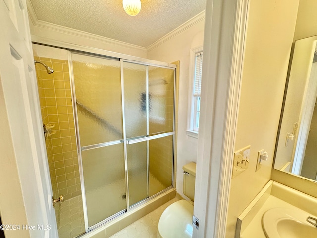 bathroom with a textured ceiling, toilet, ornamental molding, and a shower with door