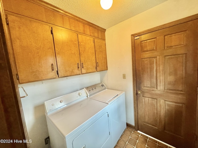 laundry room with a textured ceiling, light tile patterned floors, cabinet space, and washer and dryer