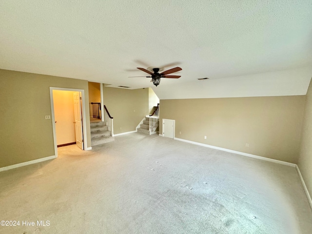 interior space featuring a textured ceiling, light colored carpet, and vaulted ceiling