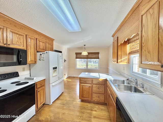 kitchen featuring light countertops, hanging light fixtures, a sink, and black appliances