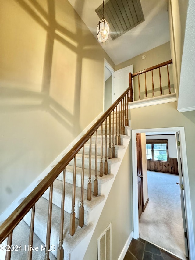 staircase featuring carpet floors, baseboards, a high ceiling, and visible vents