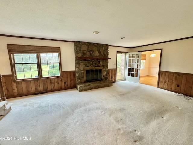 unfurnished living room featuring visible vents, wainscoting, a fireplace, and a textured ceiling