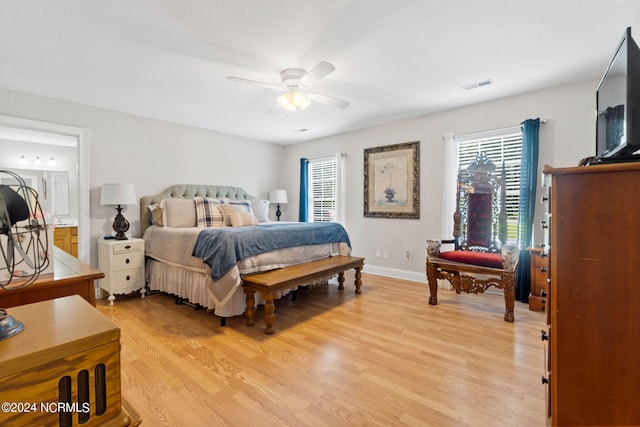 bedroom featuring multiple windows, connected bathroom, ceiling fan, and light hardwood / wood-style flooring