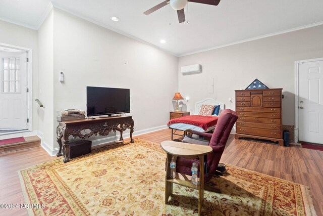 living room with a wall unit AC, light wood-type flooring, ceiling fan, and ornamental molding