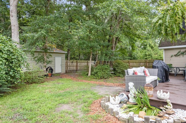 view of yard with a deck, an outdoor living space, and a storage shed