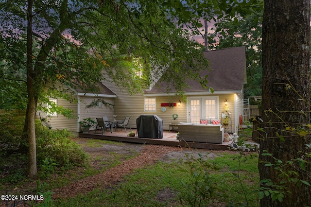 back house at dusk featuring a wooden deck, an outdoor hangout area, and french doors