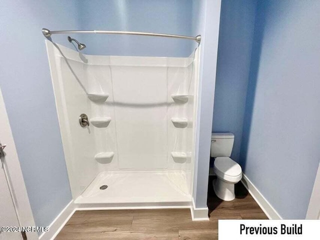 bathroom with hardwood / wood-style flooring, a shower, and toilet