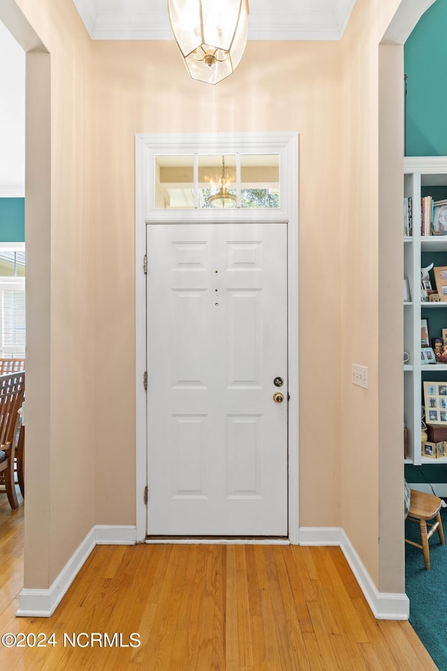 foyer with an inviting chandelier, ornamental molding, and hardwood / wood-style floors