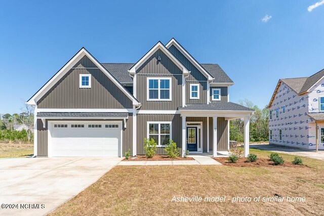 view of front facade featuring a garage, a front yard, and covered porch