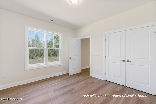 unfurnished bedroom with light wood-type flooring and a closet