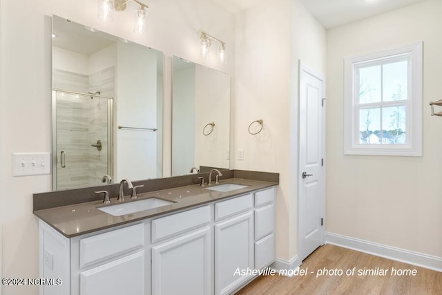 bathroom featuring dual vanity, wood-type flooring, and an enclosed shower