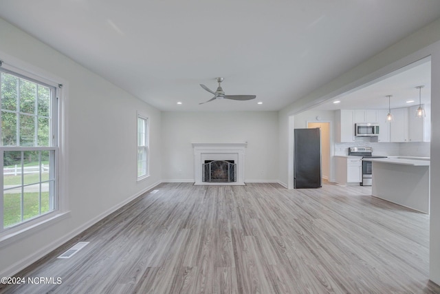 unfurnished living room featuring light hardwood / wood-style floors, a wealth of natural light, and ceiling fan