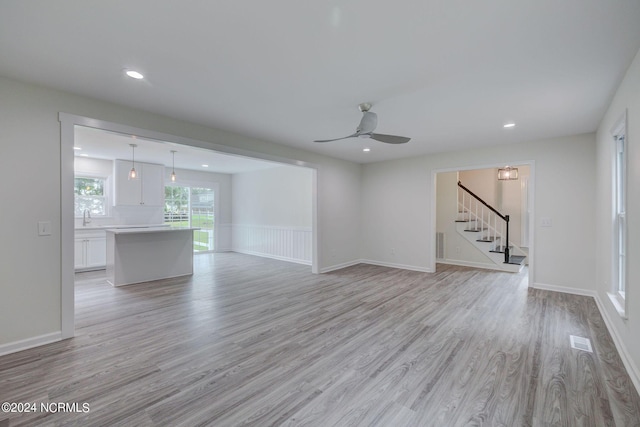 unfurnished living room with ceiling fan, light hardwood / wood-style floors, and sink