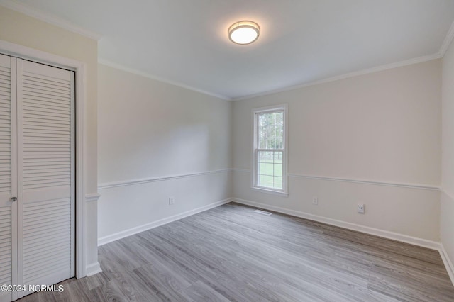 unfurnished bedroom with a closet, ornamental molding, and light wood-type flooring