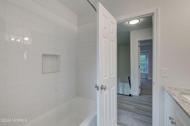 bathroom with vanity, wood-type flooring, and tiled shower / bath