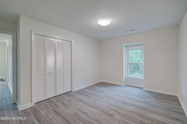 unfurnished bedroom with light wood-type flooring and a closet