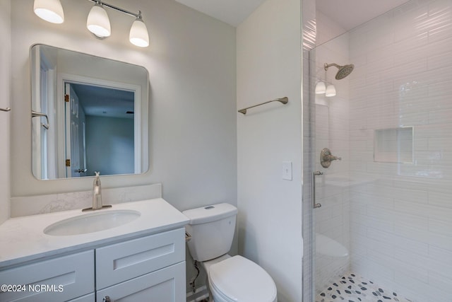 bathroom featuring vanity, toilet, and a shower with door