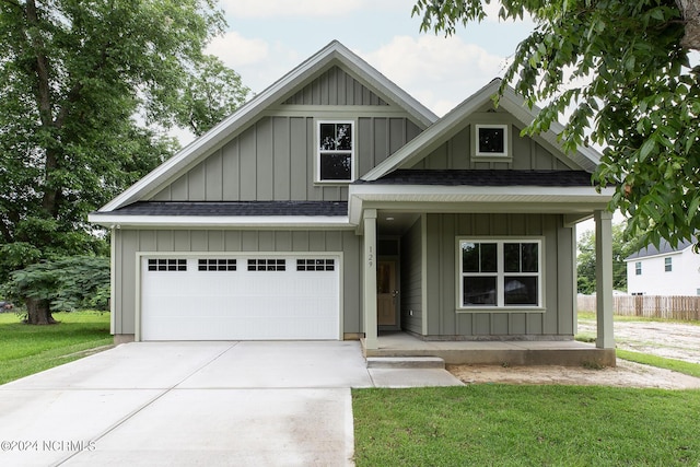 view of front facade with driveway, a shingled roof, board and batten siding, and fence