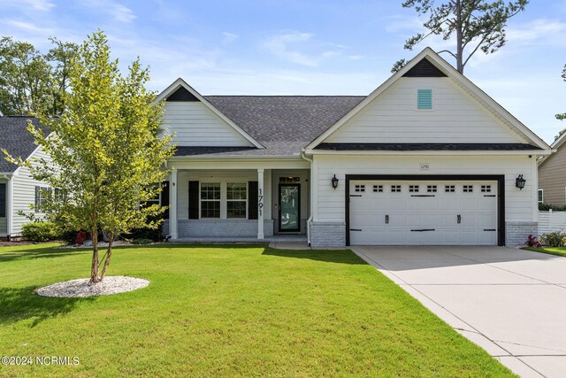 view of front of home with a garage, a front yard, and covered porch