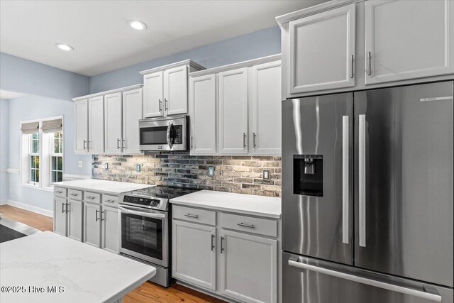 kitchen featuring white cabinetry, stainless steel appliances, sink, hanging light fixtures, and light stone counters