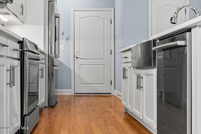 kitchen with backsplash, light stone countertops, white cabinets, and appliances with stainless steel finishes