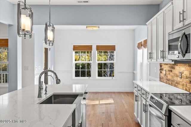 kitchen featuring tasteful backsplash, white cabinets, light stone countertops, and stainless steel appliances