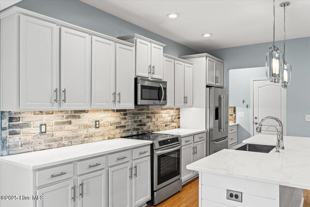 kitchen with sink, hanging light fixtures, dishwasher, an island with sink, and white cabinets