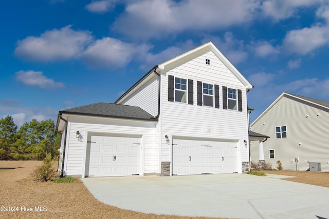 view of side of home featuring driveway, central AC unit, and stone siding