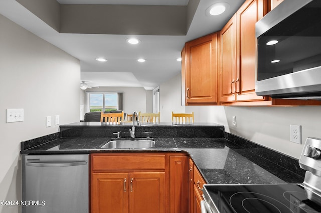 kitchen with sink, stainless steel appliances, dark stone counters, and ceiling fan