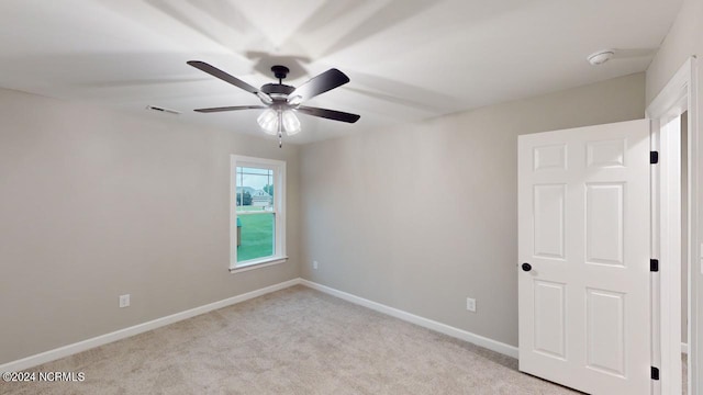 unfurnished room with light colored carpet and ceiling fan