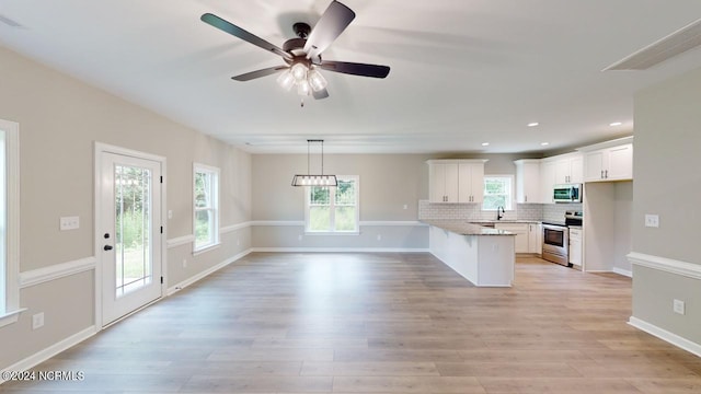 kitchen with appliances with stainless steel finishes, backsplash, light stone counters, white cabinets, and kitchen peninsula