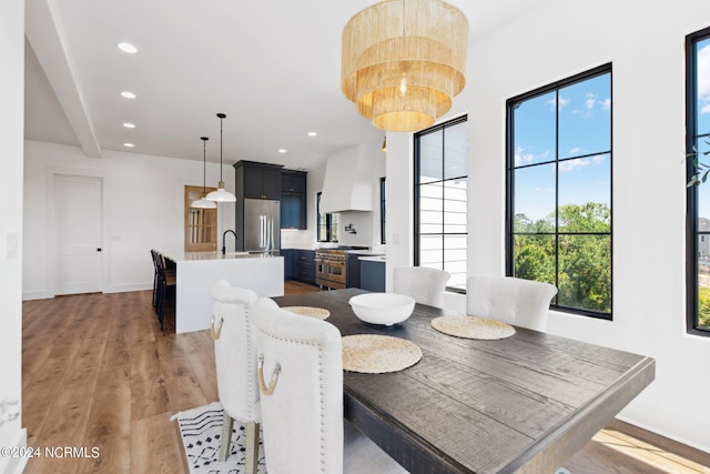 dining space featuring sink, a notable chandelier, and light hardwood / wood-style floors