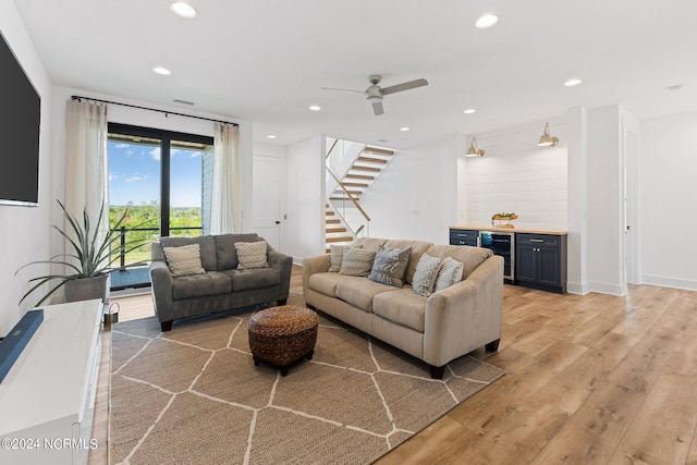 living room featuring ceiling fan, indoor bar, beverage cooler, and light hardwood / wood-style flooring