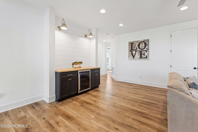 bar with butcher block countertops, hanging light fixtures, beverage cooler, and light wood-type flooring