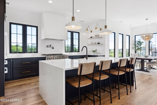 kitchen with an island with sink, light hardwood / wood-style floors, a kitchen breakfast bar, and decorative light fixtures