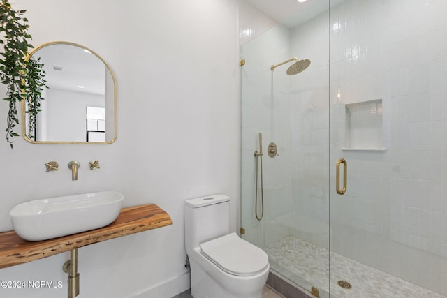 bathroom with sink, a shower with shower door, and toilet