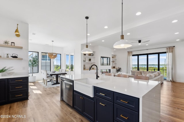 kitchen featuring hanging light fixtures, dishwasher, sink, and a center island with sink