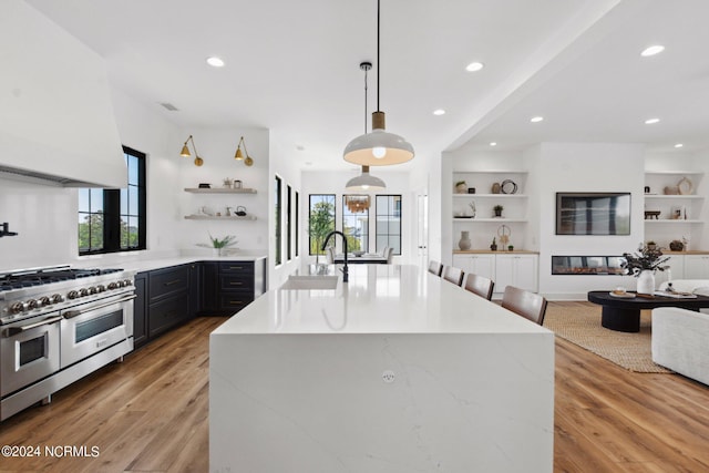 kitchen featuring plenty of natural light, decorative light fixtures, sink, and range with two ovens