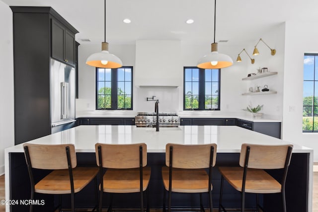 kitchen with built in refrigerator, sink, an island with sink, and plenty of natural light